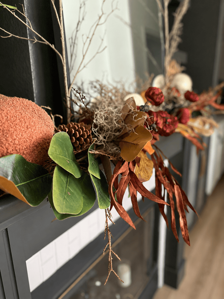Layered fall mantle with textured pumpkin, magnolia leaves, pinecone, moss and burgundy accents