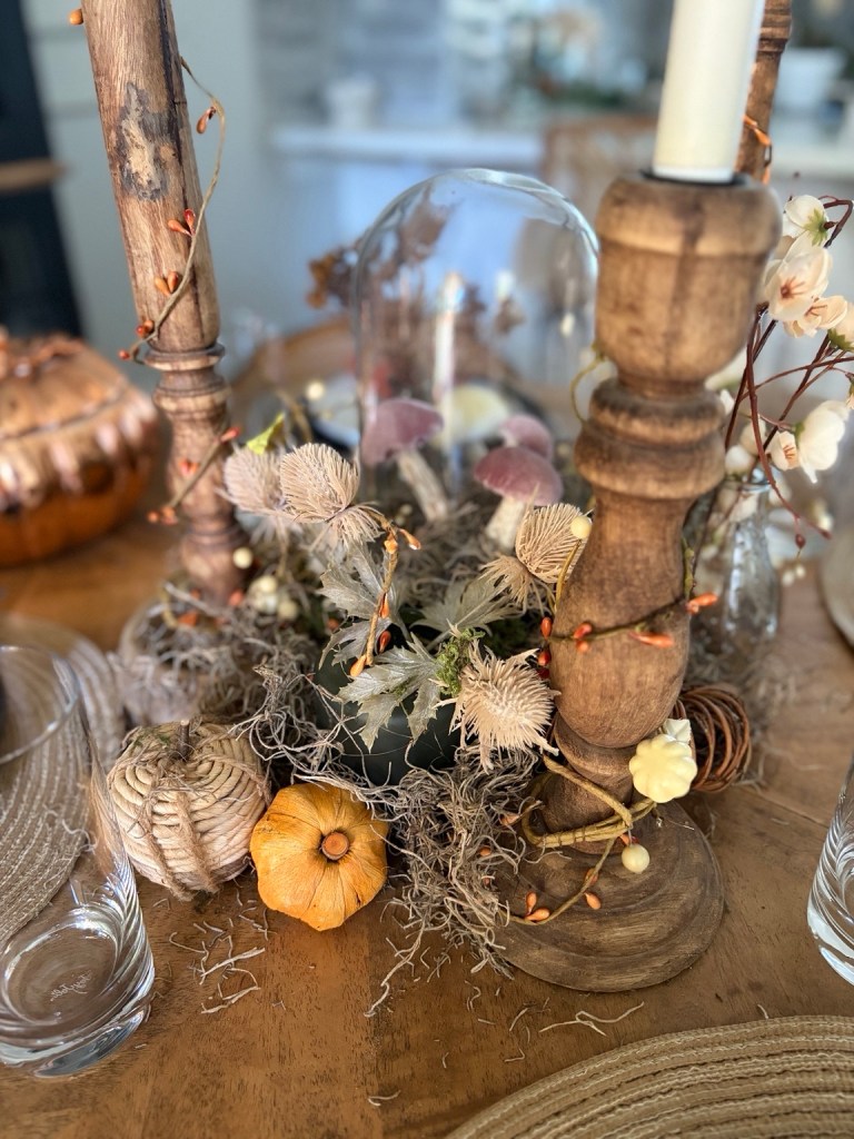 Fall table centerpiece with rustic candlesticks, pumpkins, moss and glass cloche