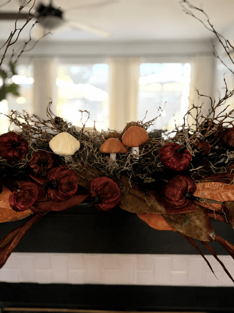 Woodland fall mantle with mushrooms, burgundy pumpkins, moss and natural branches