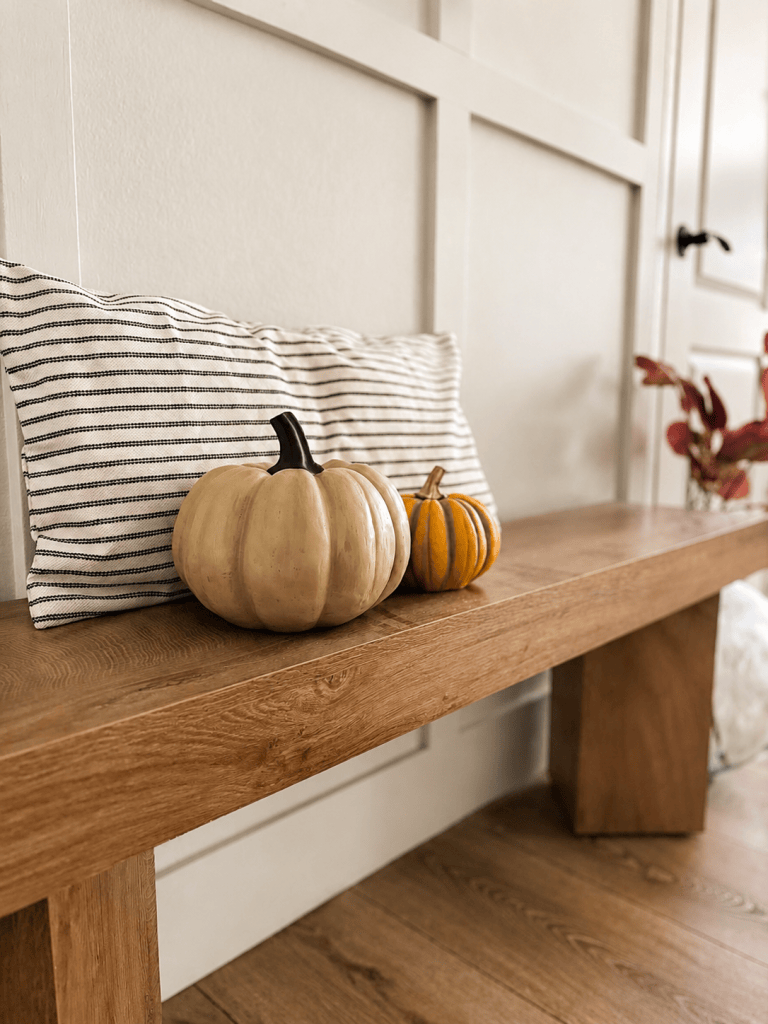 Cream and orange pumpkins styled on a wood entryway bench