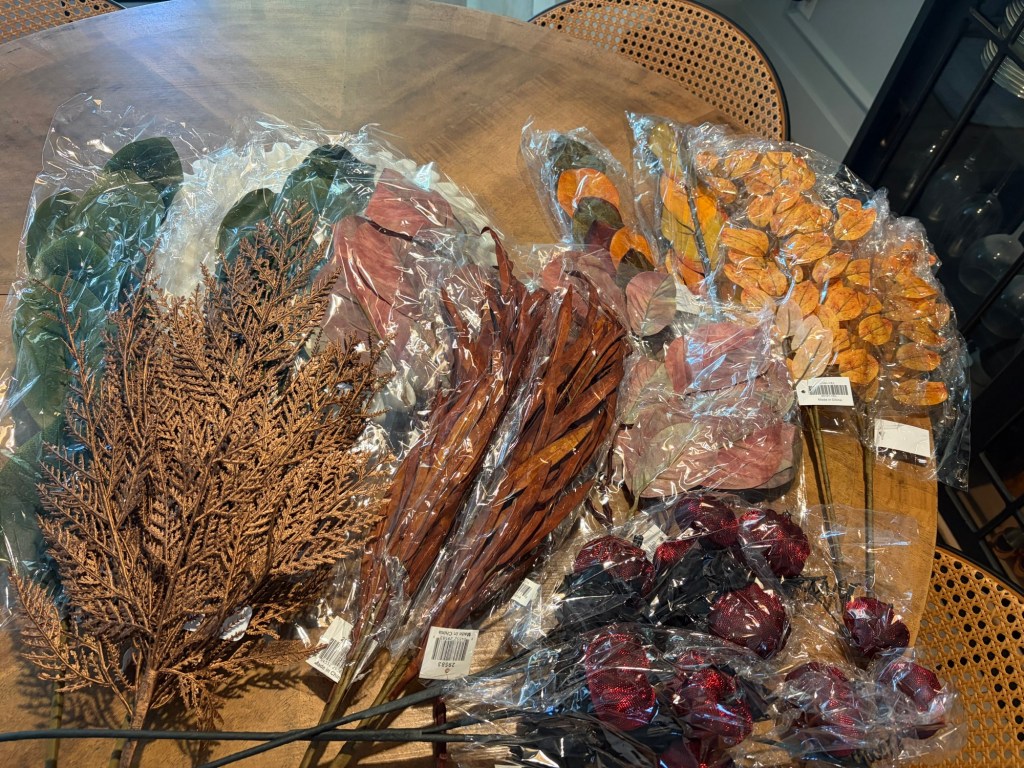 Fall stems, greenery, branches and burgundy pumpkin picks used to create a layered fall mantle