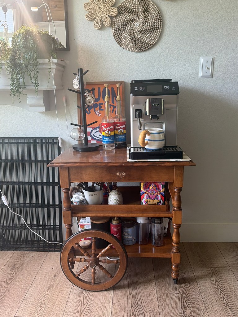 Organized coffee station with espresso machine, syrup bottles, and coffee tools on a vintage tea cart